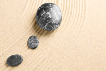Fototapeta na wymiar Zen garden stones on beige sand with pattern, flat lay. Space for text