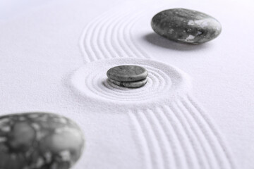 Fototapeta na wymiar Zen concept. Stones and pattern on white sand, closeup