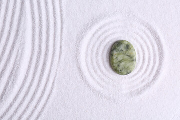 Fototapeta na wymiar Zen concept. Stone and pattern on white sand, top view. Space for text