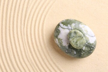 Zen concept. Stones and pattern on beige sand, top view. Space for text