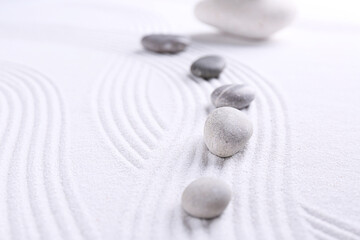 Fototapeta na wymiar Zen garden stones on white sand with pattern, space for text