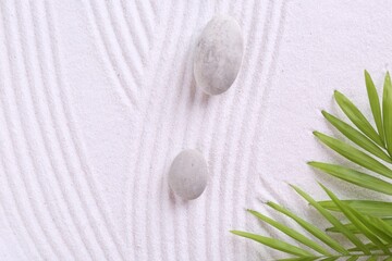 Fototapeta na wymiar Zen garden stones and green leaves on white sand with pattern, flat lay