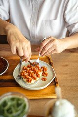 Woman take croffles, delicious breakfast. Croissant as waffle. Dessert and drinks table. Vertical format. Flat lay concept.