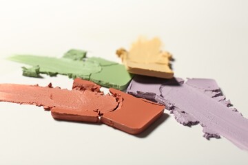 Samples of different color correcting concealers on white background
