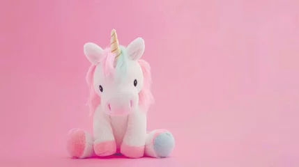 Fotobehang Adorable pink plush unicorn toy with a fluffy mane sitting against a soft pink background. © tashechka