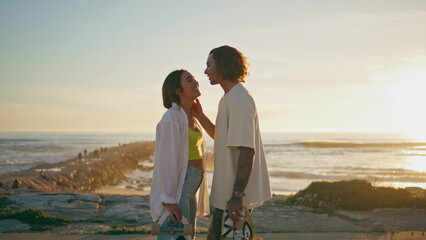 Romantic lovers kissing on sunrise beach. Skaters couple looking sea horizon