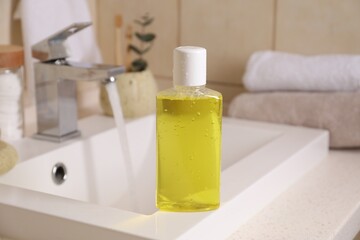 Fresh mouthwash in bottle on sink in bathroom, closeup