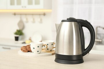 Modern electric kettle on table in kitchen. Space for text