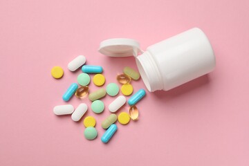 White bottle and different vitamin pills on pink background, top view