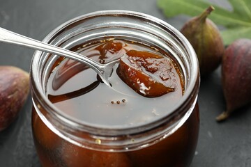 Jar of tasty sweet jam and fresh figs on black table, closeup