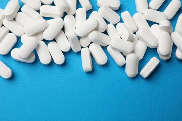 Vitamin pills on light blue background, top view. Space for text