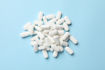 Vitamin pills on light blue background, top view