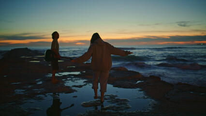 Couple silhouettes enjoying sundown ocean beach. Man playing guitar night beach