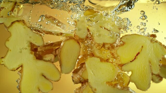Super Slow Motion Shot of Ginger Slices Falling into Water at 1000fps.