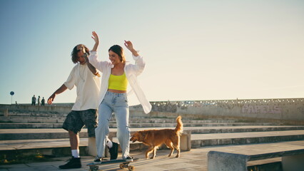 Cute skaters learning skateboard tricks street. Couple having fun riding skate