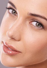 Portrait, beauty and woman with skincare, cosmetics and shine on a grey studio background. Face, person and model with glow and grooming with healthy skin and wellness with makeup and dermatology