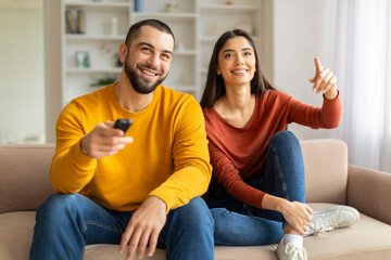 Portrait Of Happy Caucasian Couple Watching Tv While Relaxing At Home Together