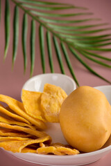 On white children's plate unusual shape, delicious candied fruits and whole mango are laid out. Whole ripe mango along with slices candied fruit, is beautifully served on plate in shape hare's head. 