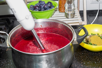 Making tkemali sauce. A saucepan with plum puree whipped in a blender and seasonings nearby