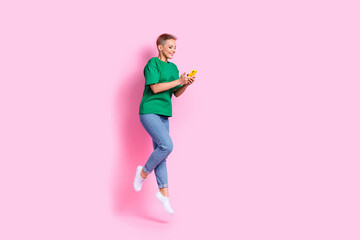 Full size photo of smart girl dressed green t-shirt fly look at impressive internet speed on smartphone isolated on pink color background