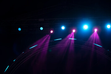 Purple rays from stage spotlights on a dark background.