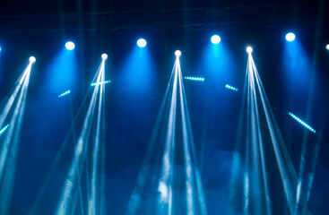 Rays of white light from stage spotlights on a blue smoky stage background. The beginning of a...
