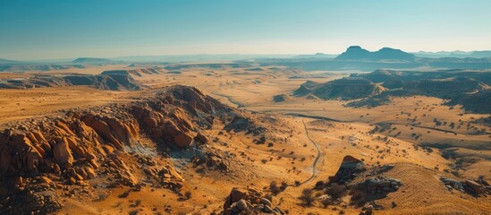 Fototapeta premium A wide desert landscape stretches far, with towering mountains in the background.