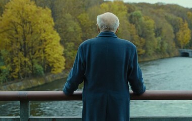 An elderly man standing on a bridge