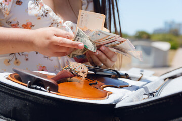 closeup unrecognizable woman counting money after working with her violin on street