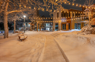 Night view of snow-covered Civic Plaza benches in downtown Canmore, Alberta, Canada