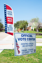 Residential street intersection with yard sign, vote banner flag show Official Vote Center in...