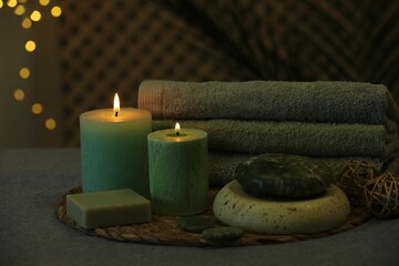 Spa composition. Burning candles, stones, soap and towels on grey table