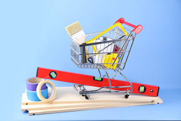 Small shopping cart with paint and renovation equipment on light blue background