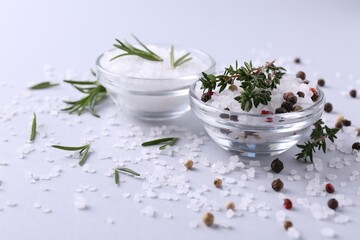 Fototapeta na wymiar Salt with peppercorns, thyme and rosemary in bowls on light table, closeup