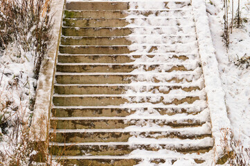 A half of staircase covered in snow. The steps are wet and slippery. The snow is piled up on the steps, making it difficult to climb