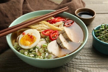 Delicious ramen in bowl on wooden table, closeup. Noodle soup