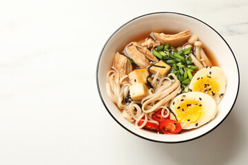 Bowl of delicious ramen on white marble table, above view. Noodle soup