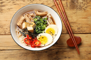 Noodle soup. Bowl of delicious ramen and chopsticks on wooden table, top view