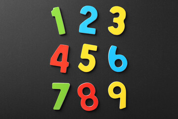 Colorful numbers on black background, flat lay