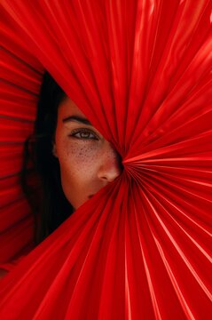 Mujer morena mirando detr&aacute;s de un abanico rojo, amor de verano, p&oacute;ster fiesta de verano en local de lujo en Espa&ntilde;a, close-up mujer espa&ntilde;ola seduciendo 