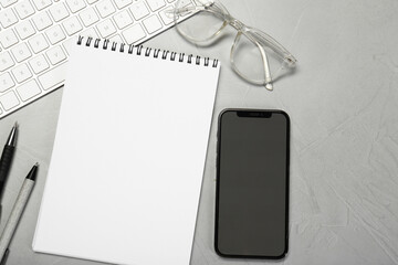 Naklejka premium Flat lay composition with open notebook and smartphone on light grey table