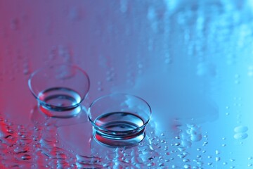 Pair of contact lenses on wet mirror surface. Space for text