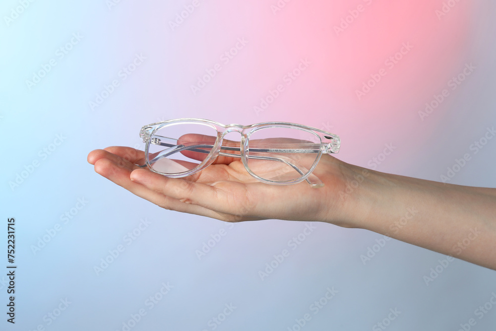 Canvas Prints Woman holding glasses with transparent frame on color background, closeup