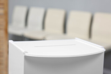 White ballot box on blurred background, closeup. Space for text