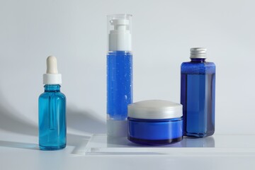 Different containers with cosmetic products on light background