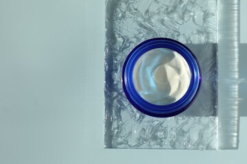 Jar of moisturizing cream on light blue background, top view. Space for text