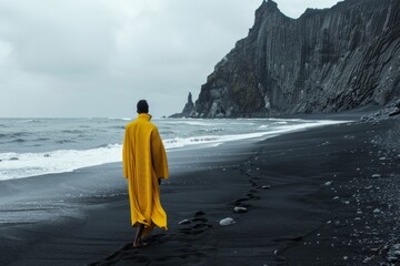 Mujer con abrigo amarillo paseando por una playa de arena negra, fotografía editorial minimalista moda upcycling