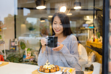 Woman enjoy tea time in coffee shop with window reflection