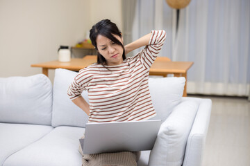 Woman suffer from the neck tensed muscles fatigued after using laptop computer for so long at home