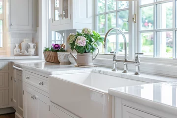 Deurstickers A beautiful sink in a white modern farmhouse kitchen with a chrome faucet, white apron sink, and white granite in front of bright windows. © Joe Hendrickson